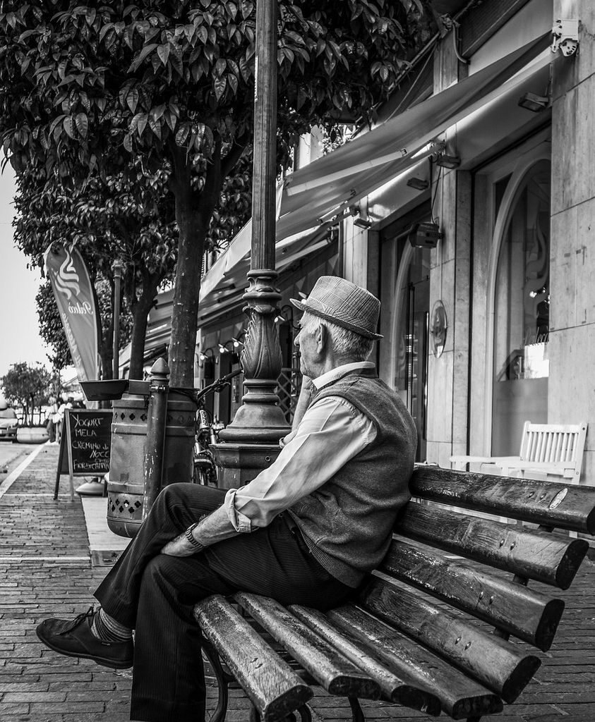 Puede ser una imagen en blanco y negro de 1 persona, fumando, banco, calle y cordón de vereda